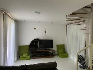 a living room with a tv and two green chairs at BANGALÔ - Varandas do Mar - Praia de Itacimirim in Camaçari