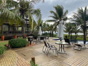 a patio with a table and chairs and umbrellas at BANGALÔ - Varandas do Mar - Praia de Itacimirim in Camaçari
