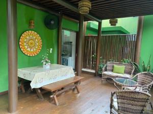 a patio with a table and chairs on a green wall at BANGALÔ - Varandas do Mar - Praia de Itacimirim in Camaçari