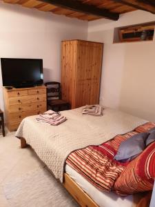 Schlafzimmer mit einem Bett und einer Kommode mit einem TV in der Unterkunft Kis Ház Apartman in Zalacsány