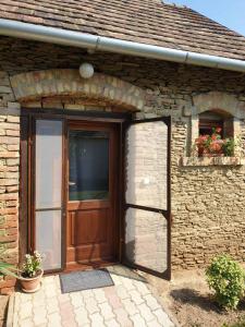 a brick house with a wooden door and a window at Kis Ház Apartman in Zalacsány