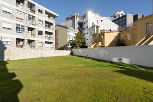une cour herbeuse avec des bâtiments en arrière-plan dans l'établissement Habitatio - Bom Sucesso, à Porto