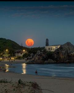 a full moon rising over a beach at night at Sintonia do Mar in São Francisco do Sul