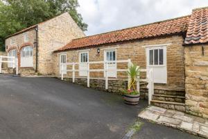 a stone house with white doors and a driveway at Prospect Farm Cottages in Allerston