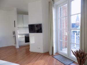 a white room with a kitchen with a tv and a window at Sylter Apartments Wilhelmstrasse in Westerland