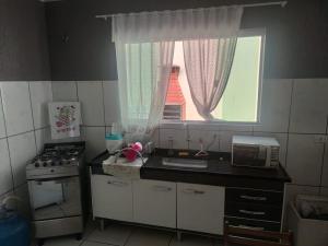 a kitchen with a stove and a window with a microwave at CASA TERREA PERUIBE 5 MIN DO CENTRO,LINDA VISTA, PRÓXIMO A TUDO. in Peruíbe +34 photos