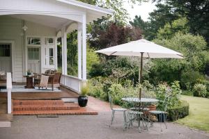 Wallingford的住宿－Wallingford Homestead，庭院配有遮阳伞和桌椅。