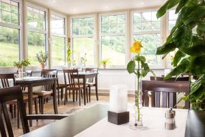 a restaurant with tables and chairs and a yellow flower in a vase at Hotel Filla Andre in Ernst
