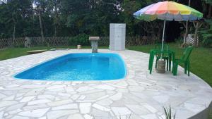 a swimming pool with a table and an umbrella at Pousada & Restaurante Chico Bento in Lambari