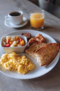 a plate of breakfast food with eggs toast and a bowl of fruit at Selina Buzios in Búzios