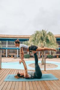 una mujer haciendo una pose de yoga con una mujer en un poste en Selina Buzios, en Búzios