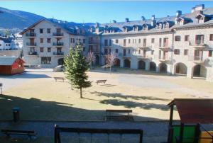 a park with benches in front of a large building at CHECK-IN CASAS Luana in Benasque