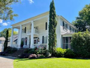 une maison blanche avec un arbre dans la cour dans l'établissement Bama Bed and Breakfast - Sweet Home Alabama Suite, à Tuscaloosa