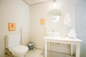 a white bathroom with a toilet and a sink at Selina Buzios in Búzios