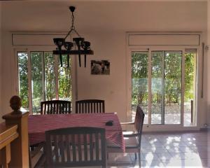 a dining room with a table and chairs and windows at Casa Bella Vista en montaña con vistas al mar y piscina privada in Cunit
