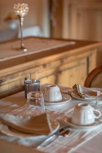 una mesa con platos blancos y cubiertos en B&B Alla Loggia dell'Imperatore, en Levico Terme