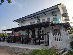 una casa blanca con una puerta de hierro negro en Kayangan Inn en Rantau Panjang