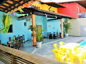 a restaurant with yellow tables and chairs and a pool at Pousada Casa Bella in Campina Grande
