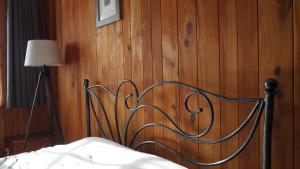 ein Bett mit einer Holzwand mit einem Metallkopfbrett in der Unterkunft Au Pied du Pont in Châteauneuf-du-Faou
