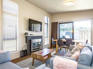 a living room with a couch and a fireplace and a table at Alpine Place - Spa and Mountain Views in Ohakune