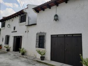 a white house with a black garage at La Capitanía in Antigua Guatemala