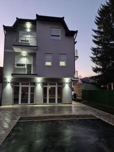 a white building with a parking lot in front of it at Apartmani Marija in Vrdnik