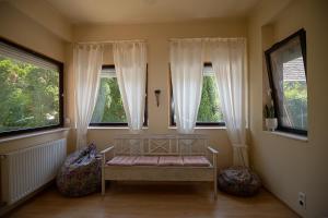 a room with a bench in front of two windows at Szélcsend Apartman in Balatonföldvár