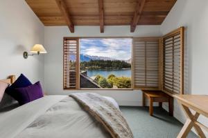 a bedroom with a large window with a view of a lake at Brunswick Lodge - Luxury - Central Queenstown in Queenstown