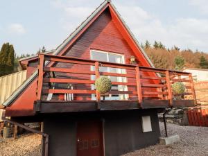 a house with a deck on the side of it at Larchfield Chalet 2 in Auchterneed