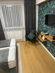 a bedroom with a bed and a chair and a television at apartament LeśnaCedzyna in Cedzyna