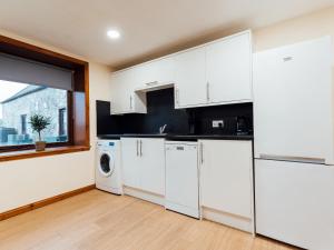 a kitchen with white cabinets and a washer and dryer at The Barn in Girthon