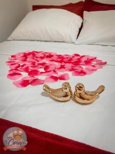 a bed with pink rose petals and two gold rings at Casa da Coruja in Rio de Janeiro
