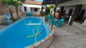 a swimming pool in a yard with blue chairs at Pousada Subindo as Dunas in Canoa Quebrada