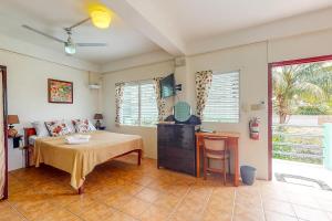 Schlafzimmer mit einem Bett, einem Tisch und einem Schreibtisch in der Unterkunft Almond Tree 3 at Island Cabanas Gold Standard Certified in Caye Caulker