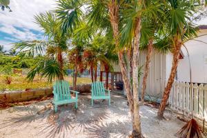 two blue chairs sitting under palm trees in a yard at Almond Tree 3 at Island Cabanas Gold Standard Certified in Caye Caulker