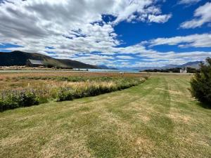 a field of grass with a body of water at Church House Beside the Lake in Lake Tekapo
