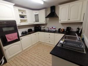 a kitchen with white cabinets and a sink at Comfy Quiet Town House in Strabane