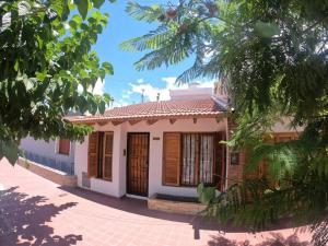 Una pequeña casa blanca con persianas de madera. en Departamento encantador en Maipú en Maipú