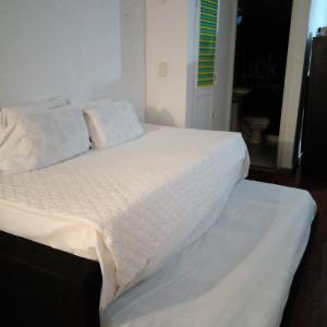 a bed with white sheets and pillows on it at @casa__grace in Cartagena de Indias