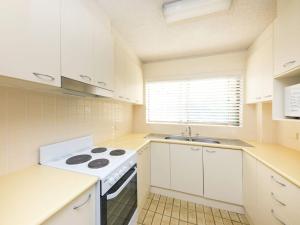 a white kitchen with a stove and a sink at Centrepoint 10 in Forster