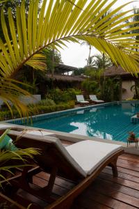 a swimming pool with a chaise lounging chairs and a palm tree at Amaya Boutique Resort in Srithanu