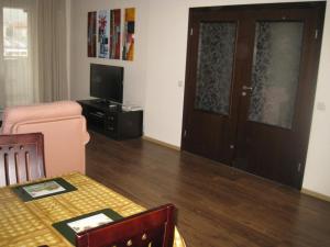 sala de estar con mesa, TV y puerta en Spacious and Cosy Apartment in Bansko Royal Towers Complex, en Bansko