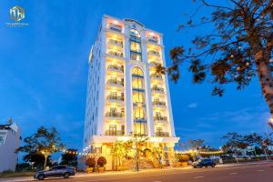 a tall white building with cars parked in front of it at Thọ Hướng Hotel - Phan Thiết in Phan Thiet