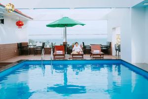 una mujer sentada en una silla junto a una piscina en Thọ Hướng Hotel - Phan Thiết en Phan Thiet