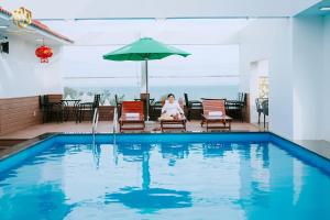 a woman sitting in a chair next to a swimming pool at Thọ Hướng Hotel - Phan Thiết in Phan Thiet