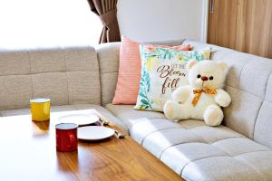 a teddy bear sitting on a couch with a table at はなハウス 2F in Ginowan