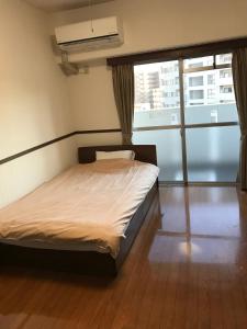 a bed in a room with a large window at Weekly & Monthly City Inn Kokura in Kitakyushu