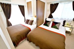 two beds in a hotel room with windows at はなハウス 2F in Ginowan