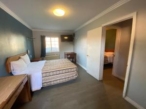 a hotel room with two beds and a door to a bedroom at Sands Inn in South Gate
