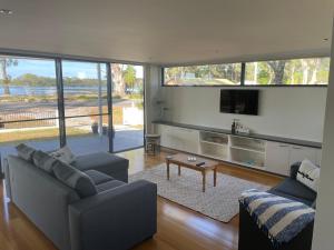 a living room with two couches and a flat screen tv at Gull Apartment in Strahan